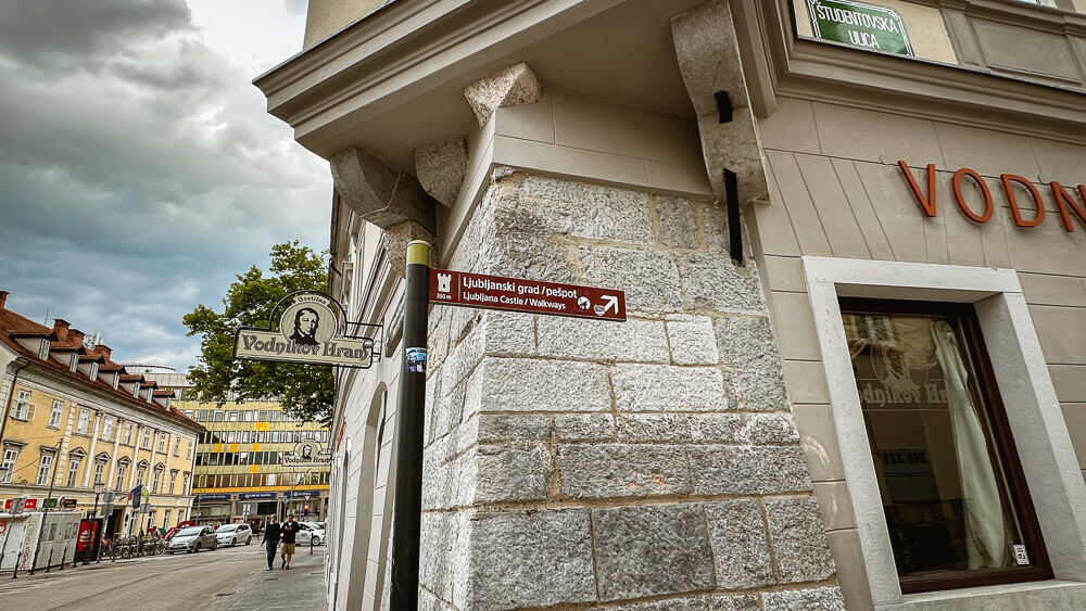 Ljubljana Castle sign on the side of a building directing you to the walking path